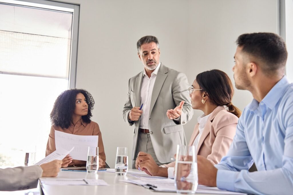 Senior company leader consulting busy employees team at office meeting.